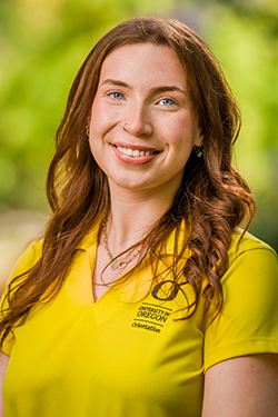 Woman with long brown hair in a yellow polo shirt