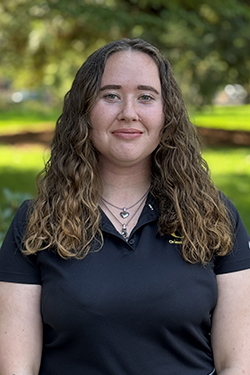 Female with long dark hair wearing a black polo shirt