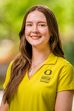 Woman with long brown hair in a yellow polo shirt