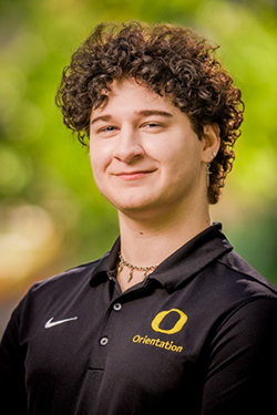 Male with short brown hair wearing a black polo shirt